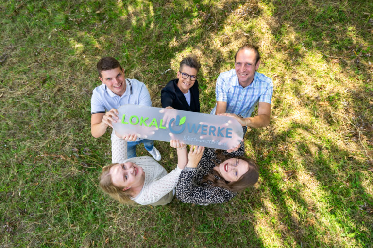 Aufnahme von Oben mit fünf Personen, die ein LokalWerke Schild hoch halten