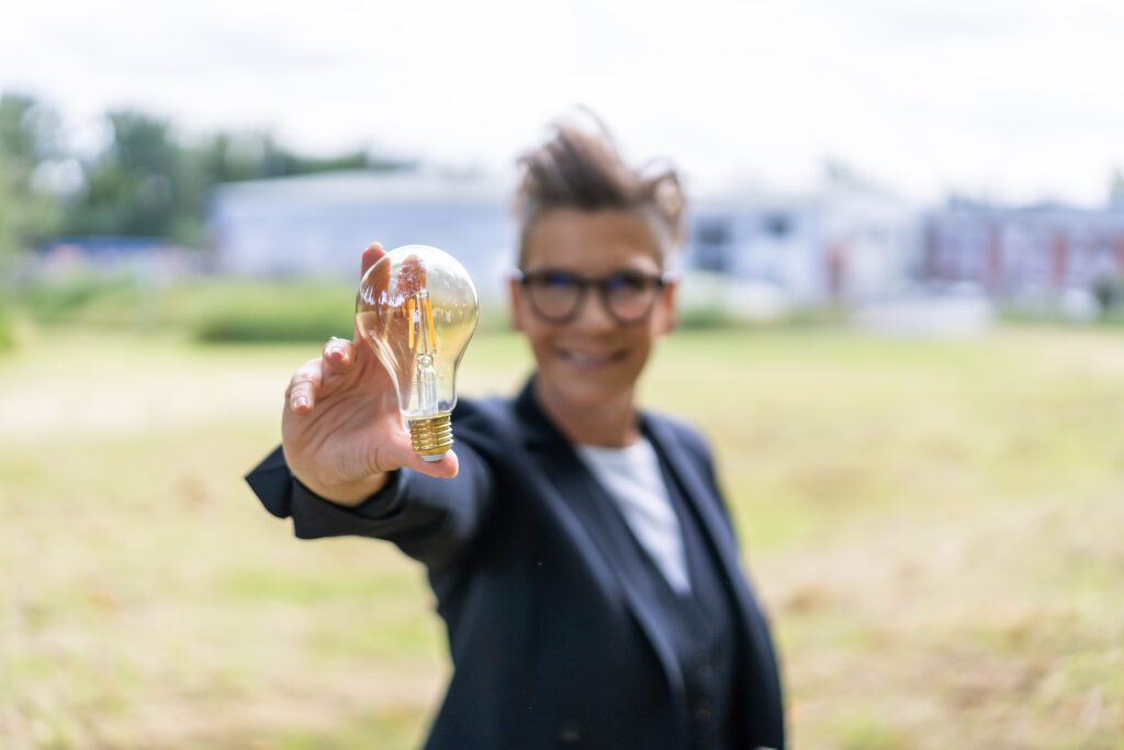 Frau zeigt eine Glühbirne in die Kamera