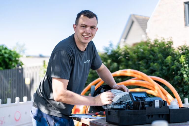 Mann in arbeitet draußen an technischem Gerät mit Kabeln im Hintergrund