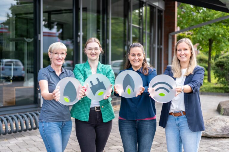 Vier MitarbeiterInnen halten jeweils ein Dekoelement mit Wasser-, Strom-, Gas- und Empfangssymbolik in den Farben der Lokalwerke