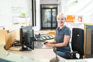 Mitarbeiterin lacht freundlich am Arbeitsplatz