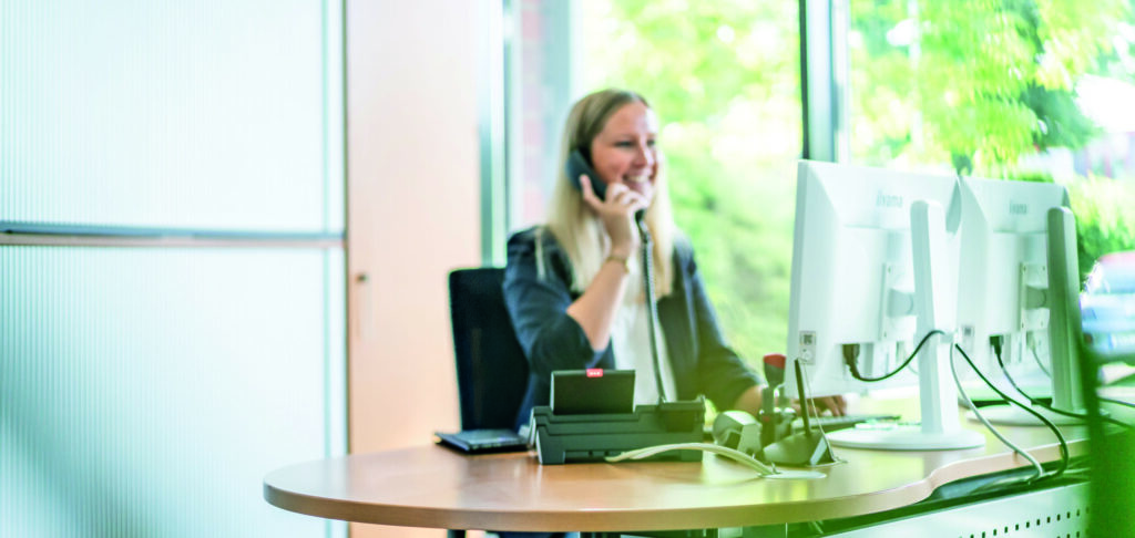 Eine Mitarbeiterin sitzt im Büro und telefoniert