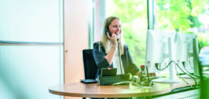 Eine Mitarbeiterin sitzt im Büro und telefoniert