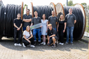 Neun Personen stehen vor Kabeltrommeln