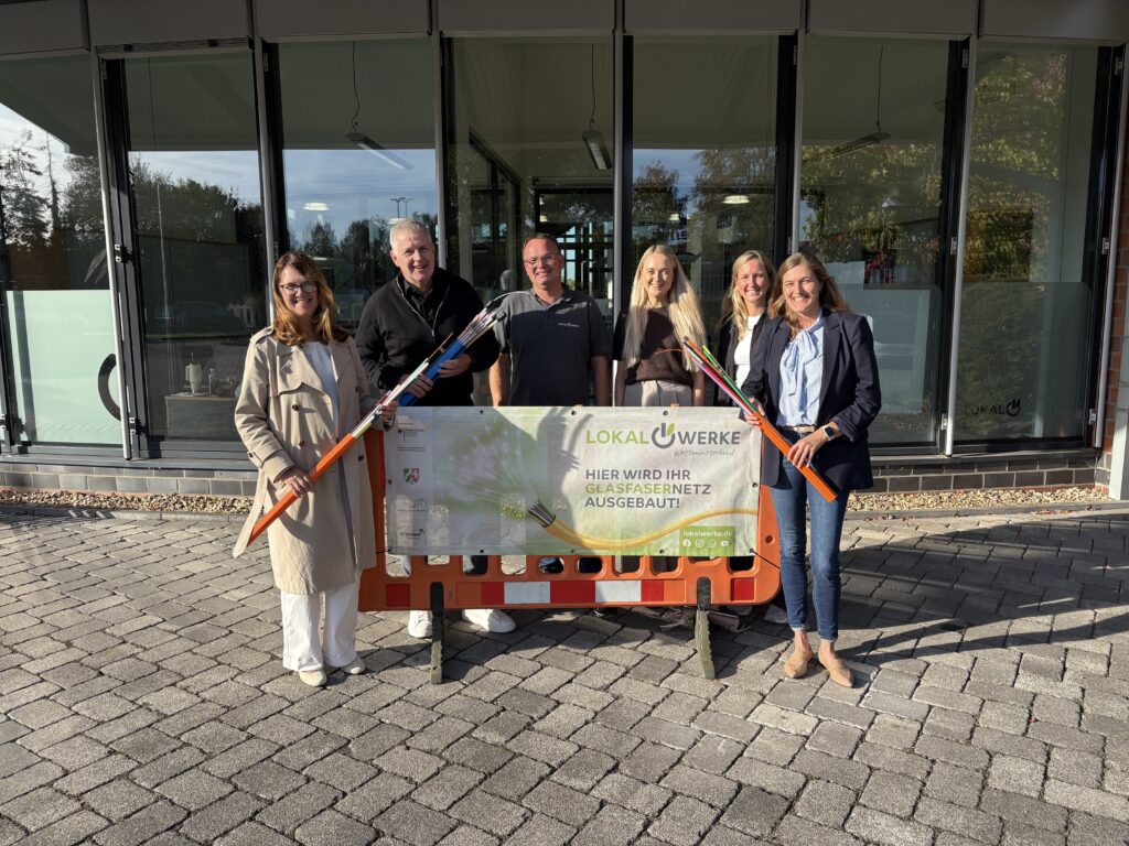 Sechs Menschen stehen vor dem Eingang der Lokalwerke Ahaus vor einem Glasfaser Banner